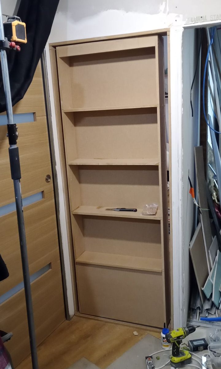 Bibliothèque en panneaux de bois, fabriquée sur mesure et ajustée dans son encadrement.