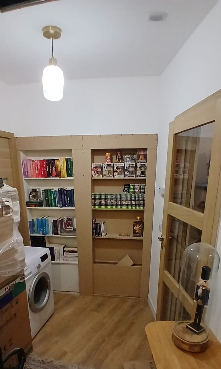 Les bibliothèques sur mesure terminées et remplies, à côté d’une porte vitrée en bois.