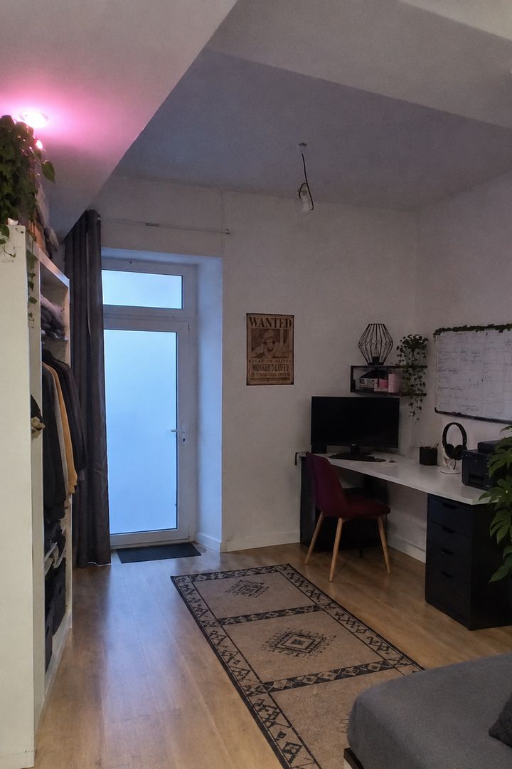 Chambre avec bureau, penderie ouverte et porte vitrée. Photo retouchée par IA à la demande des clients : certains effets personnels ont été retirés.