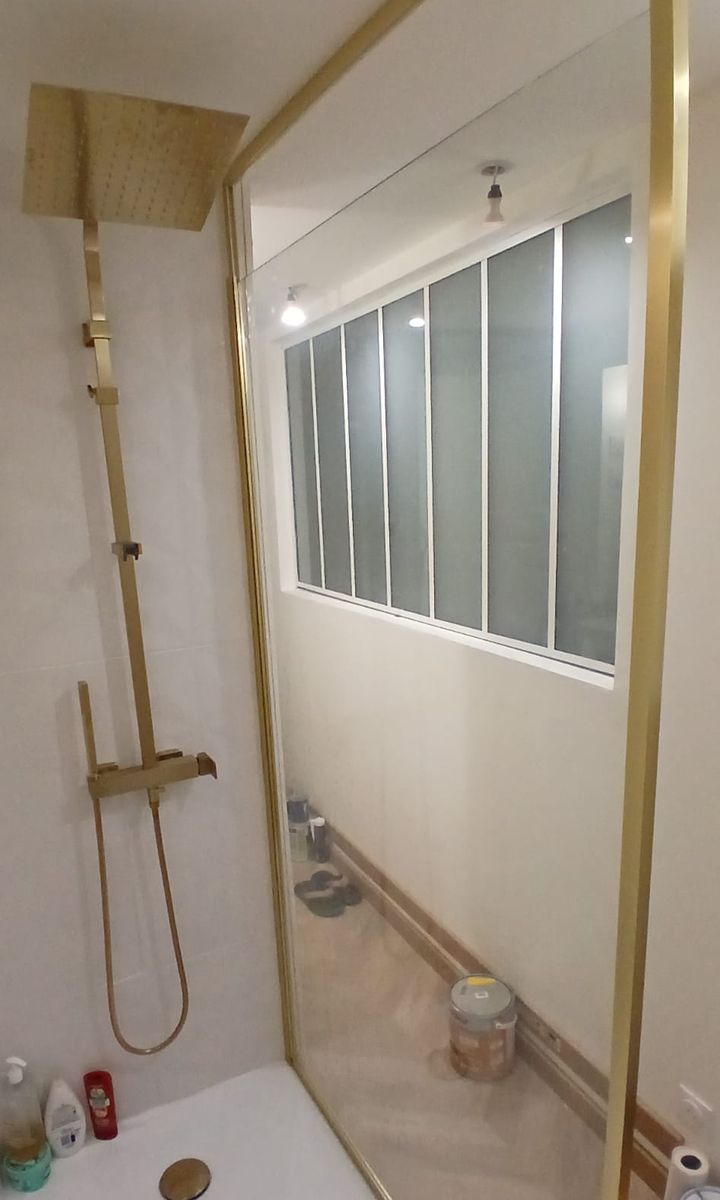Douche terminée : colonne et paroi couleur laiton, receveur blanc et verrière intérieure en verre dépoli.