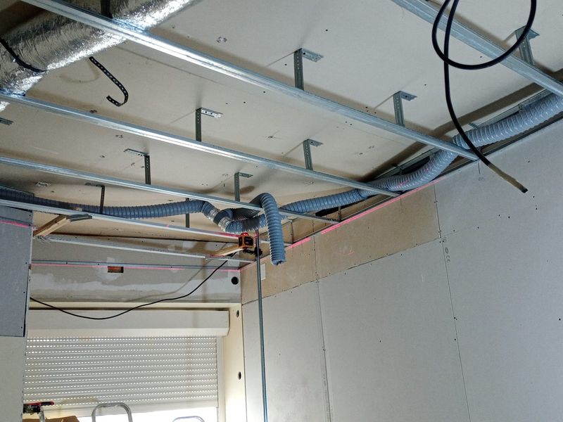 Ossature métallique du nouveau plafond, alignée au niveau laser autour des gaines.