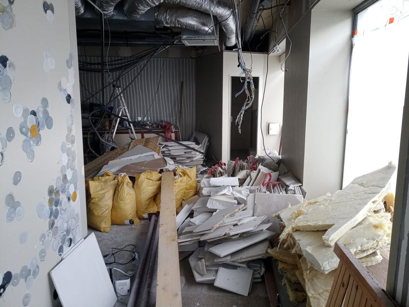 Plaques de plâtre et laine isolante déposées, entassées à côté des sacs de gravats.