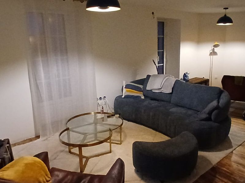 Le salon terminé : murs et plafond blancs, sol en bois, suspensions noires.