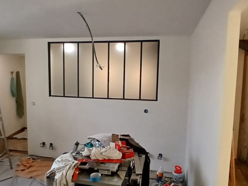 Verrière intérieure à montants noirs posée dans une cloison neuve, avant les finitions.
